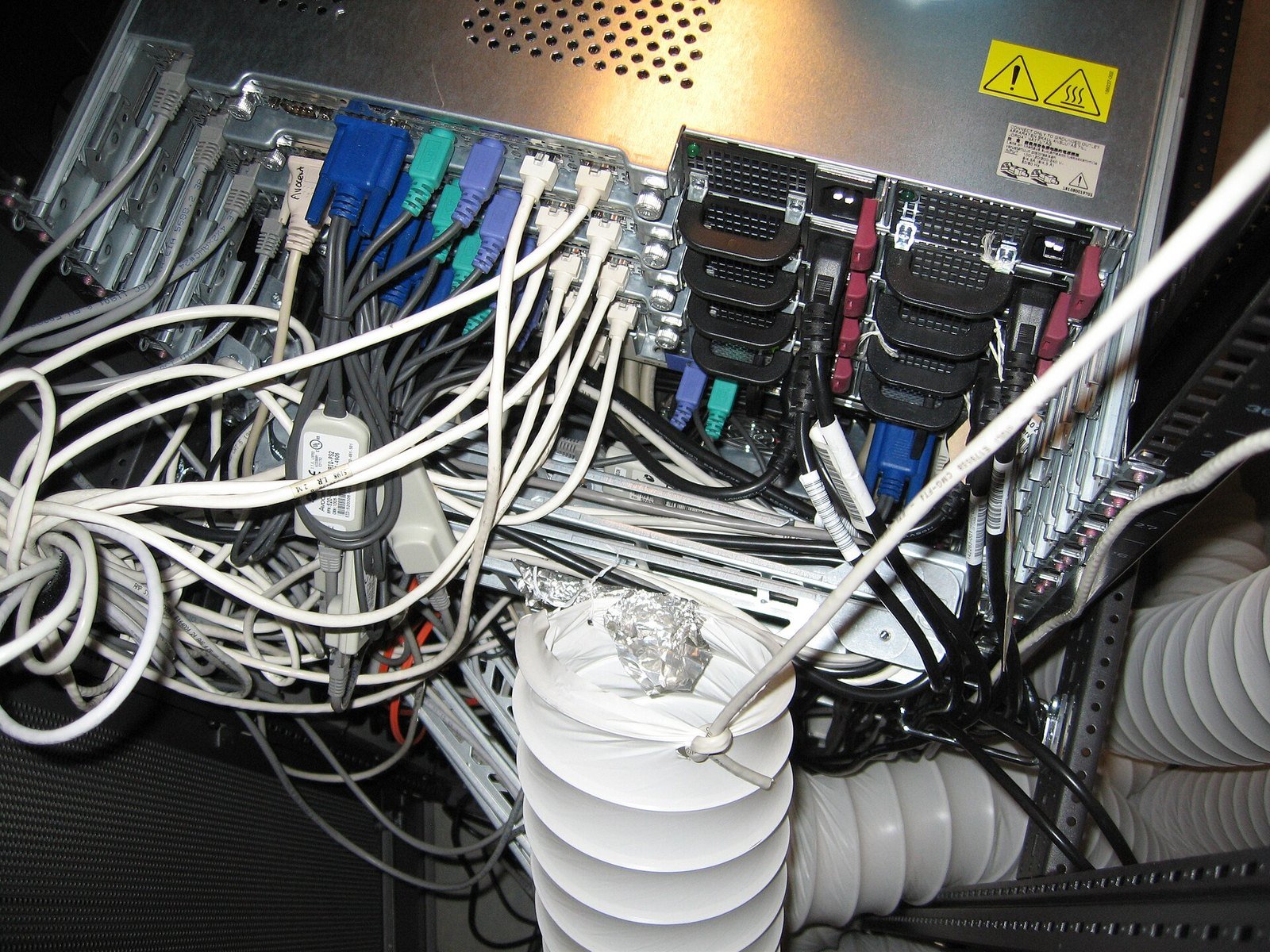 Cabling and connectors behind server racks in a computer room. <em>Photo: <a hre